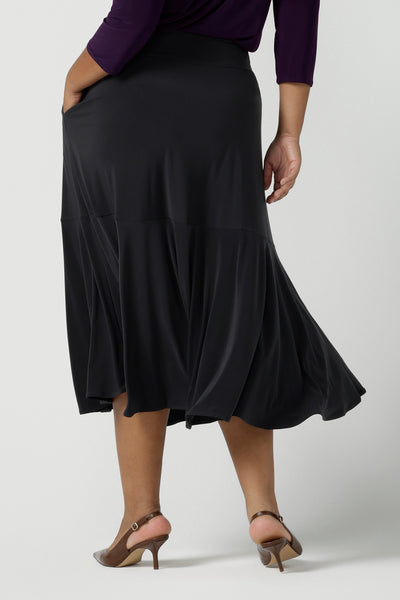 Size 16 wears the Berit Maxi skirt in Charcoal. A women's jersey work skirt with pockets in a charcoal colour. Made in Australia for women size 8 - 24. Styled back with a Purple Amethyst Vida top with 3/4 sleeves and a v-neckline.