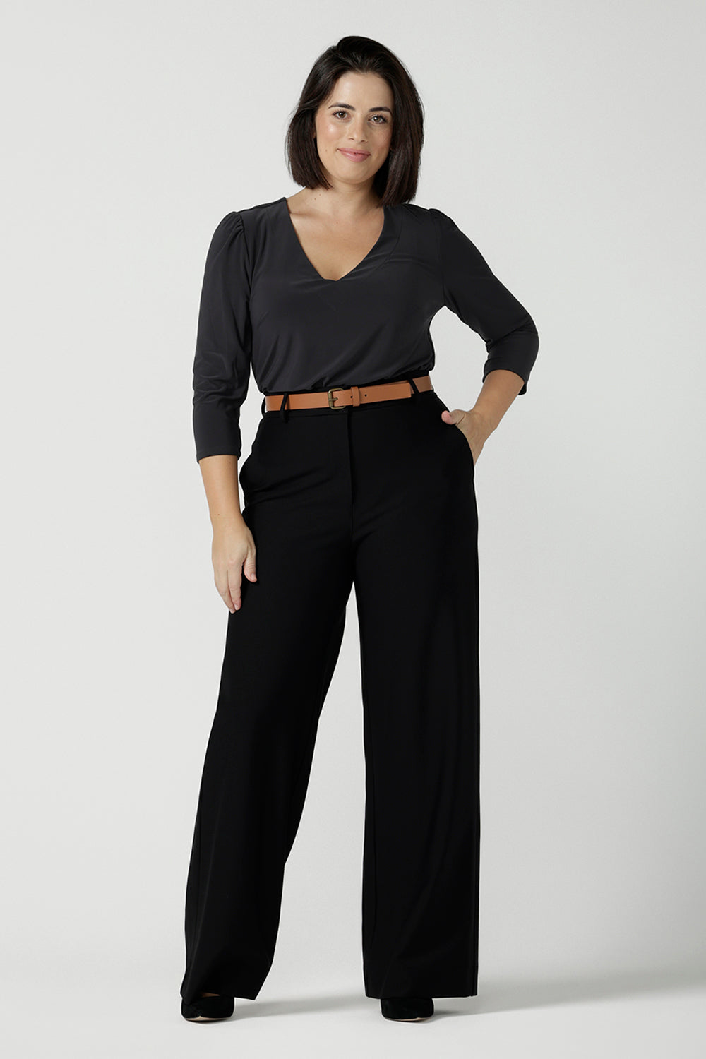A size 10 woman wears the Vida top in Charcoal, a grey work top for women with a V-neckline. Comfortable corporate workwear for women. Made in Australia for women. Size 8 - 24.