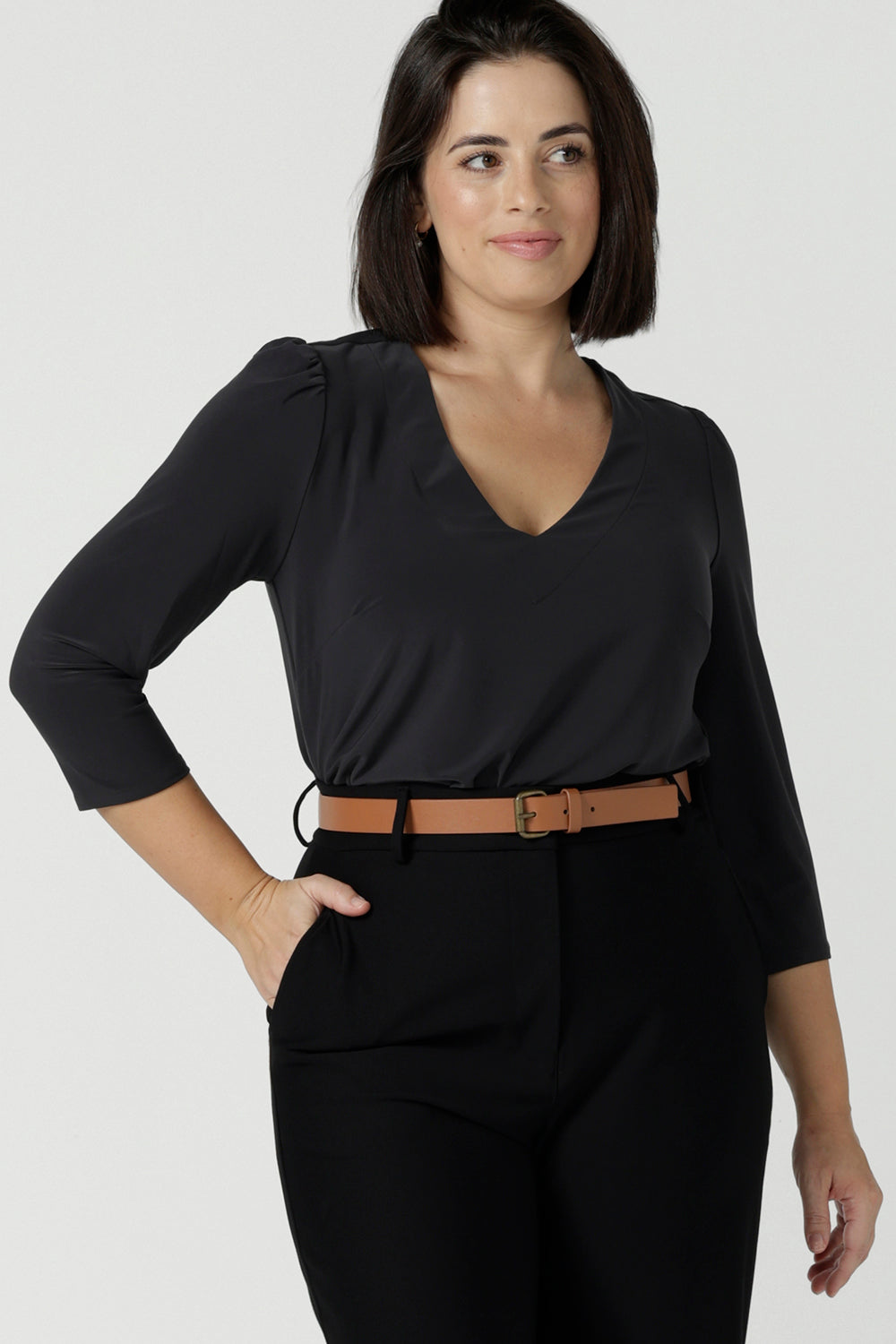 Close up of a size 10 woman wears the Vida top in Charcoal, a grey work top for women with a V-neckline. Comfortable corporate workwear for women. Made in Australia for women. Size 8 - 24.