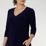 Size 10 woman wears the Vida Top in classic Navy, showcasing its flattering V-neckline and elegant 3/4 sleeves. Crafted from our signature dry-touch stretch jersey, this top offers all-day comfort and effortless style, making it the perfect choice for everything from corporate workwear to relaxed weekend dressing.