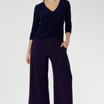 Woman wears the Vida Top in classic Navy, showcasing its flattering V-neckline and elegant 3/4 sleeves. Crafted from our signature dry-touch stretch jersey, this top offers all-day comfort and effortless style.