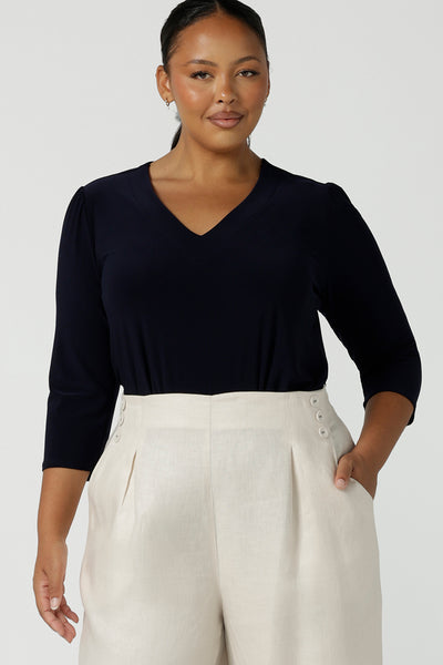 A curvy size 16 woman wears a vida top in Navy with a V-neckline and 3/4 sleeves. Made in comfortable jersey for corporate workwear to casual wear. Made in Australia for women size 8 - 24.