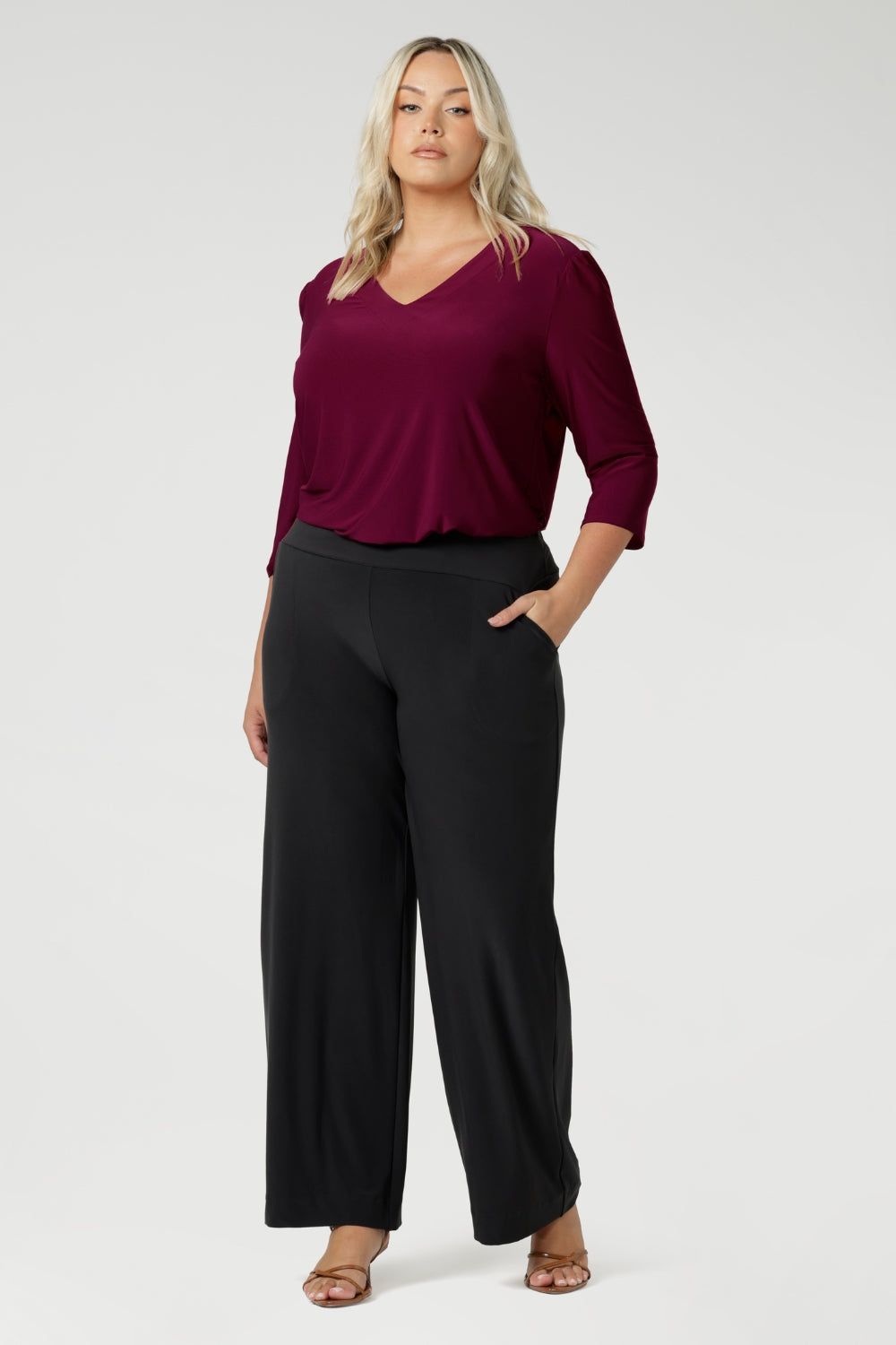 Whether paired with tailored pants for the office or dressed up for an evening out, this top combines style, versatility, and comfort in one essential piece. Size 18 model wears her Vida Top tucked into a pair of stretchy jersey pants in the colour charcoal with brown heels.