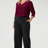 Whether paired with tailored pants for the office or dressed up for an evening out, this top combines style, versatility, and comfort in one essential piece. Size 18 model wears her Vida Top tucked into a pair of stretchy jersey pants in the colour charcoal with brown heels.