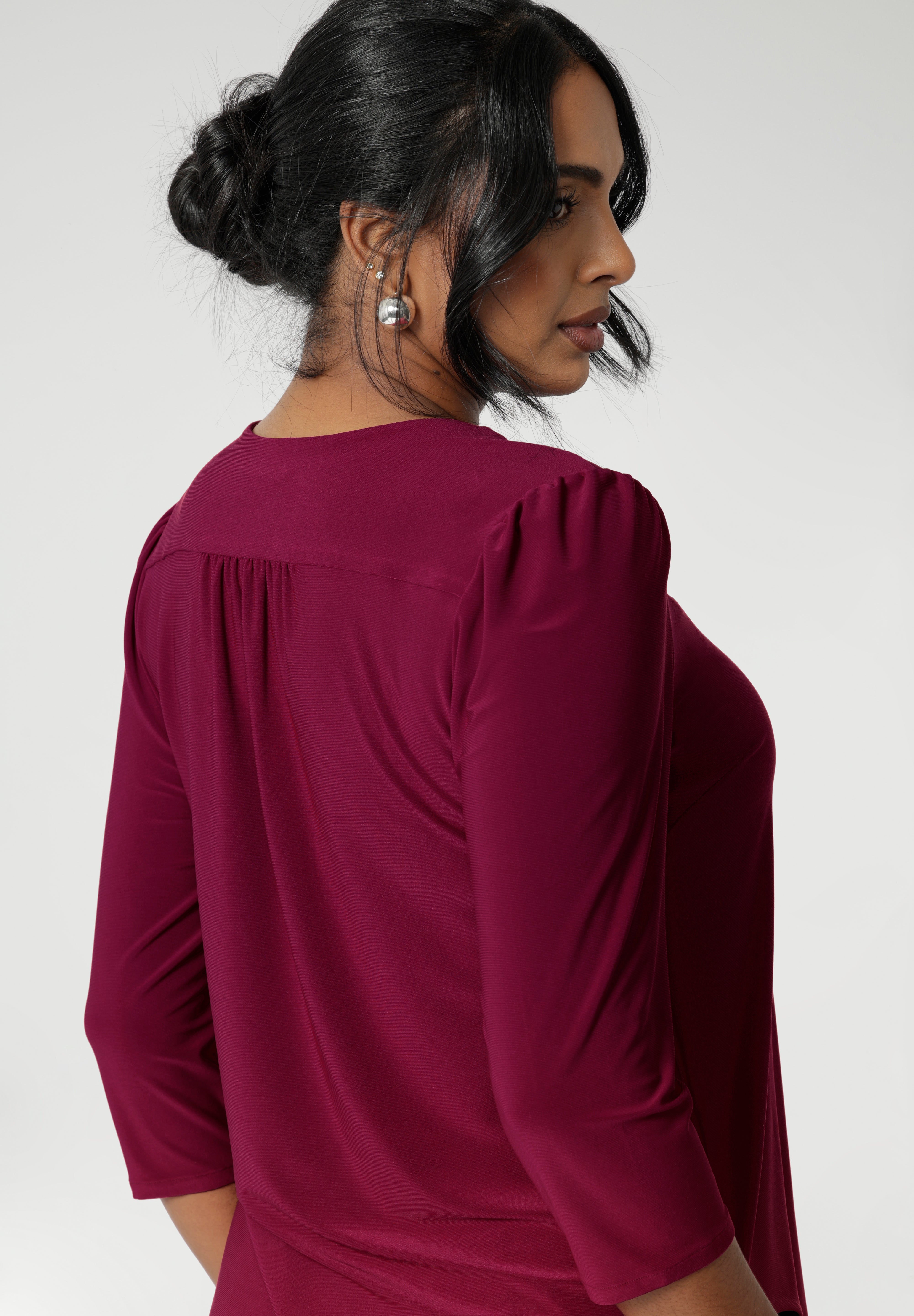 This versatile top features semi-fitted bust darts for a flattering silhouette and a classic V-neckline that enhances its elegant design. The 3/4 sleeves are detailed with tucks at the sleeve heads, adding subtle refinement to the overall look.