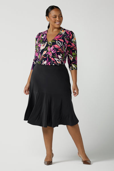 Size 16 Women wears the Berit skirt in Charcoal with pockets and tier hem. A great below knee length skirt perfect for all heights especially petite. Made in Australia for women size 8 - 24. Styled back with the Vida to in Vivid floral a bright and bold floral print on a navy base.