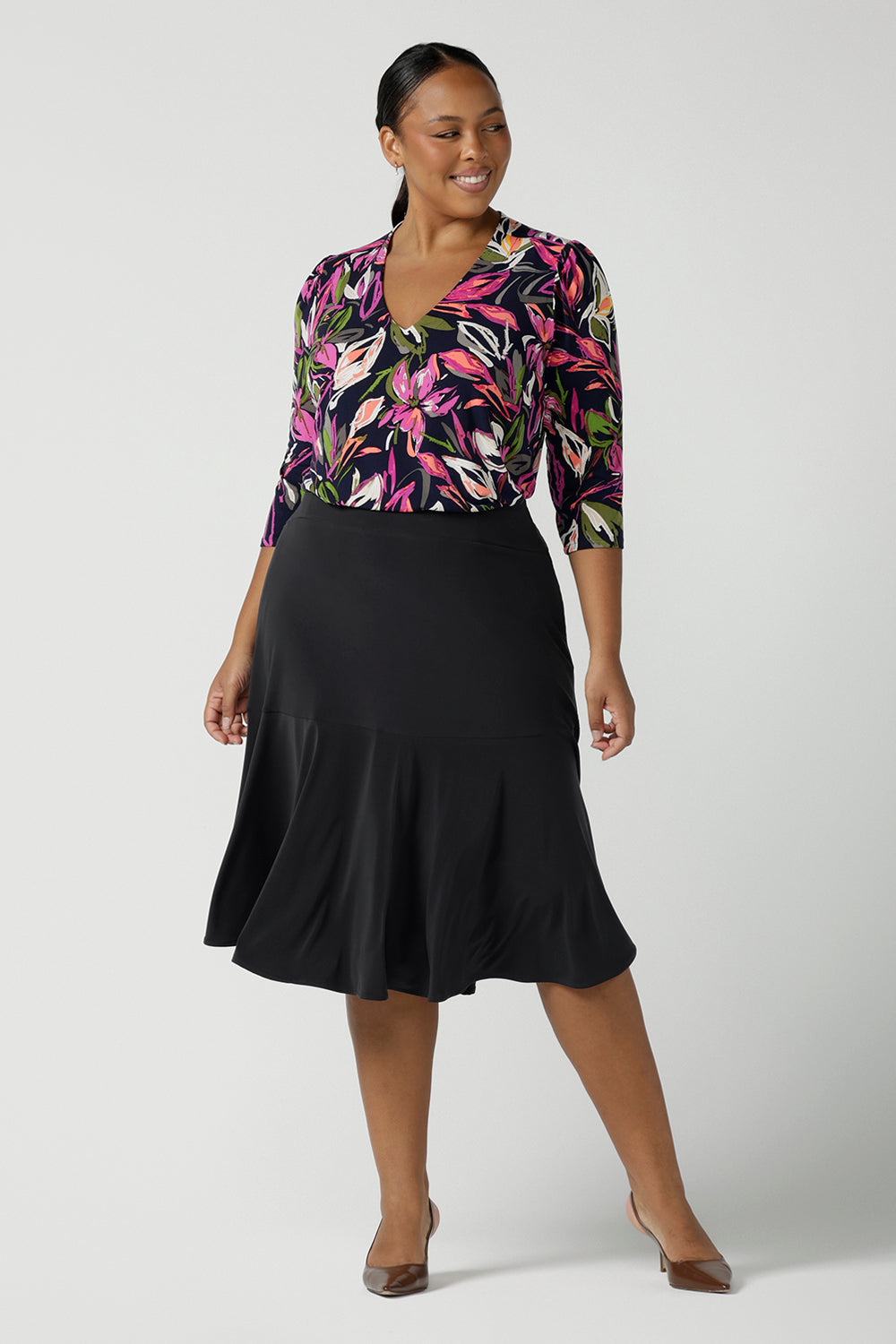 Size 16 woman wears the Vida top in Vivid Flora. A v-neckline style with 3/4 sleeves. Corporate casual work tops. Styled back with the Berit skirt in Charcoal. Made in Australia for women size 8 - 24. 