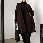 The Sorel Trench Coat is expertly tailored with a modern, sophisticated silhouette that elevates any wardrobe. Size 18 woman wears winter coat crafted from a luxurious winter-weight Modal fabric over long length black pants, black turtle neck, and high heel boots for an elevated workwear look. 