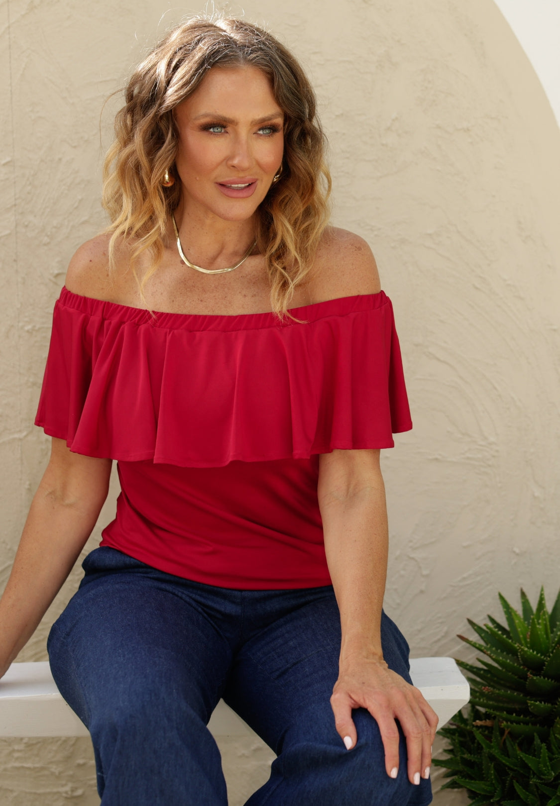 Woman over 40s wearing red off the shoulder top and organic hemp denim jeans by online Australian fashion brand Leina & Fleur.