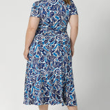 Plus size model wears short sleeve dress, designed with delicate tucks on the shoulder, midi length skirt & full wrap design. From workday sophistication to event-ready weekend comfort. This dress is built on a slinky jersey base, offering a soft, stretchable fit that moves with everybody to ensure comfort and style. Available in sizes 8-24.