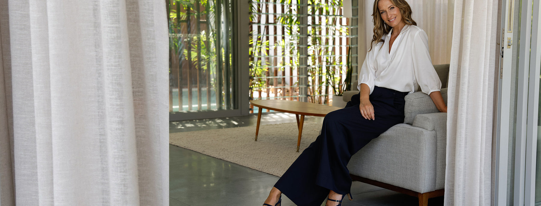 Fashion for the 40-plus woman, a mature woman wears soft tailoring, wide-leg navy blue trousers with a pull on white shirt, to showcase how soft tailoring creates easy elegance for style over 40.