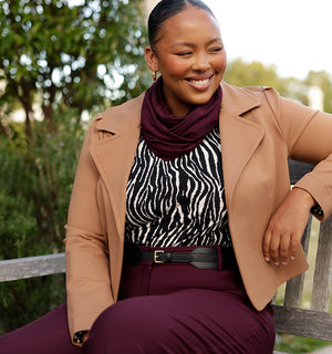 Layering up for winter, a woman wears a zebra print top with tan jacket and bamboo jersey scarf, all made in Australia. Shop winter style online now at Leina and Fleur.