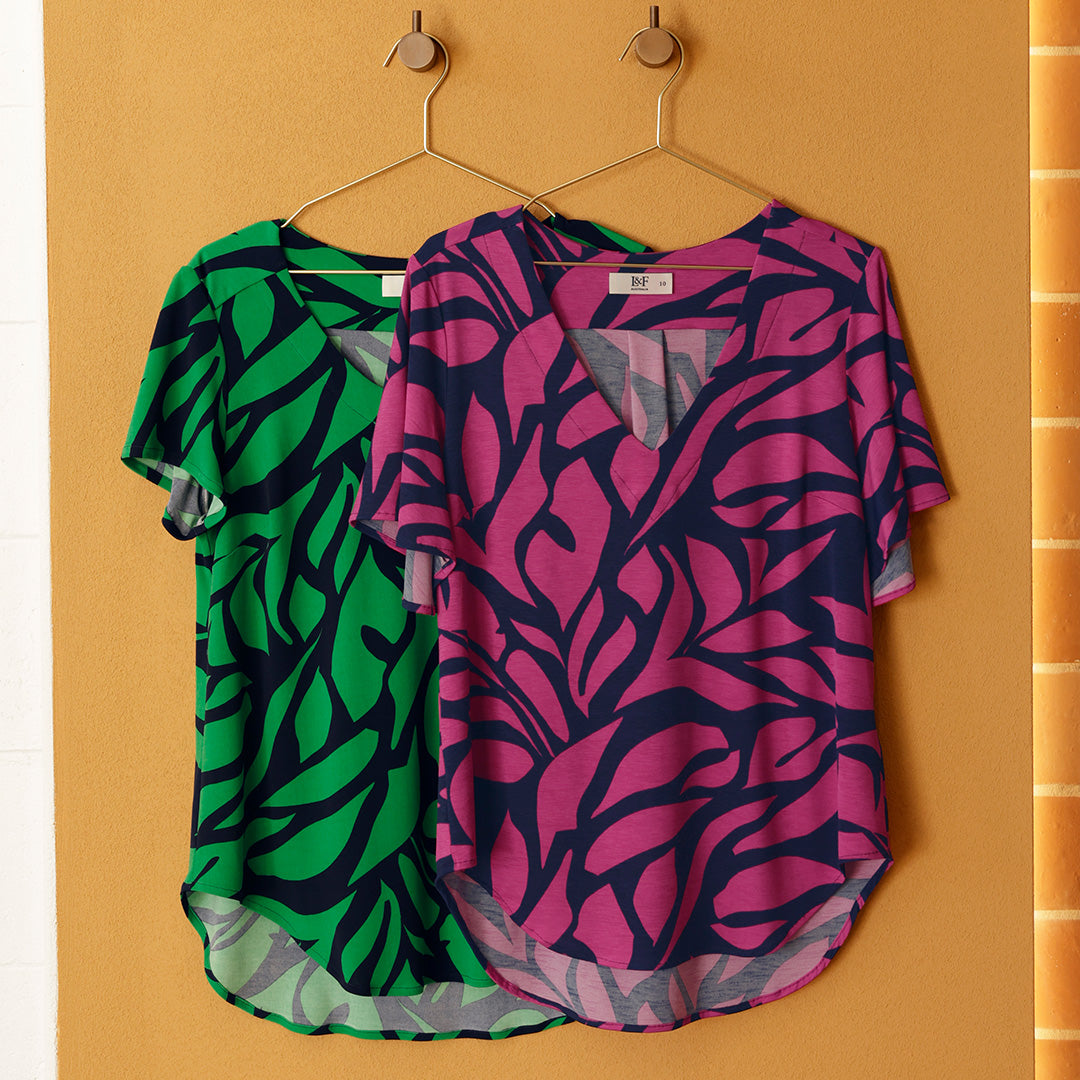 Two jersey tops for women by Australian and New Zealand women's clothing brand hang side by side. To the left a round, neck short sleeve top in green and navy print jersey makes a great summer top for women. To the right, a pink and navy jungle print top with flutter sleeves makes a great workwear top for ladies. Shop tops online in sizes 8 to 24.