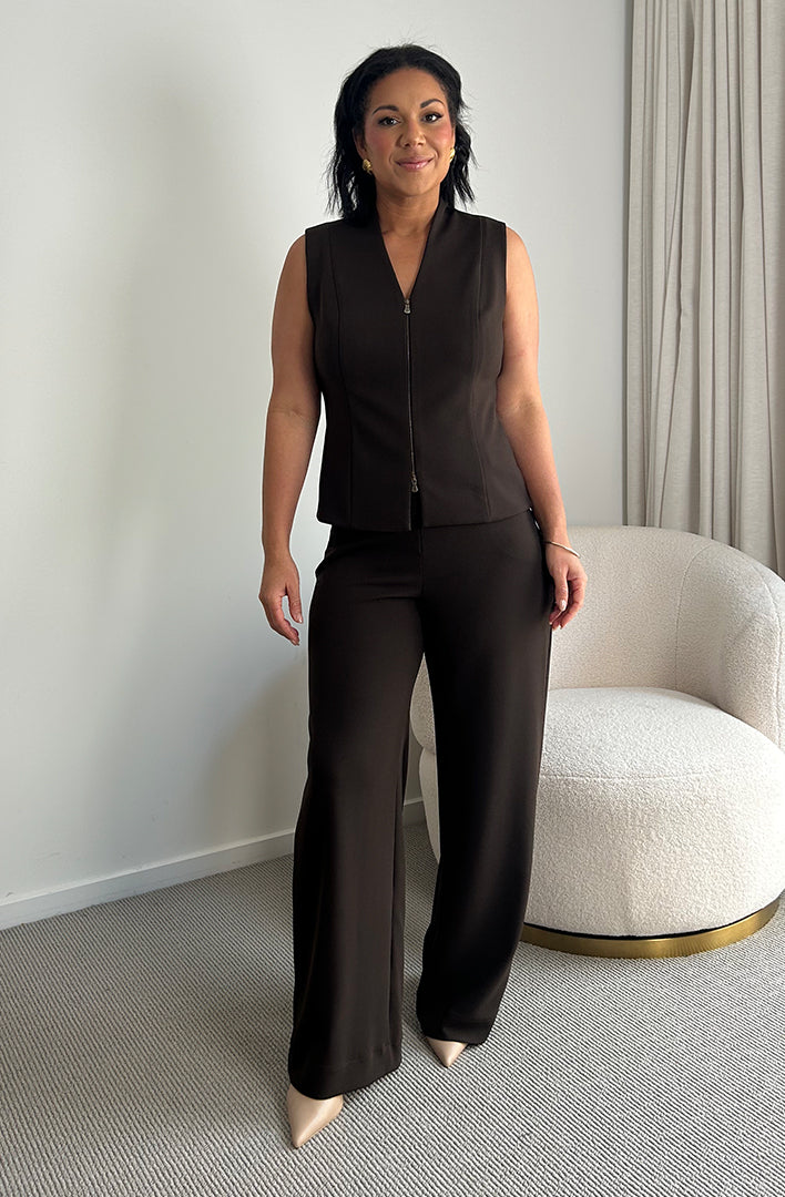 Showing a work wear outfit for professional women, a size 10 woman wears a cocoa brown zip front vest and brown wide leg pants. Both vest and pants for women are made in Australia in sizes 8-24 by women's clothing brand, Leina + Fleur. 