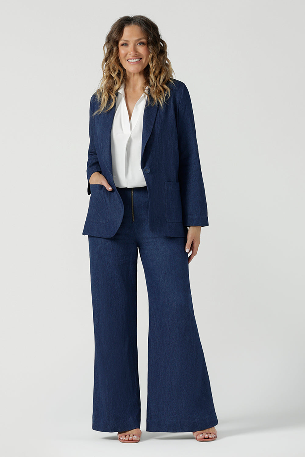 A size 10 woman wears the Vintage Denim Xavier Blazer. A button front style blazer with pockets. Made in Australia for women size 8-24