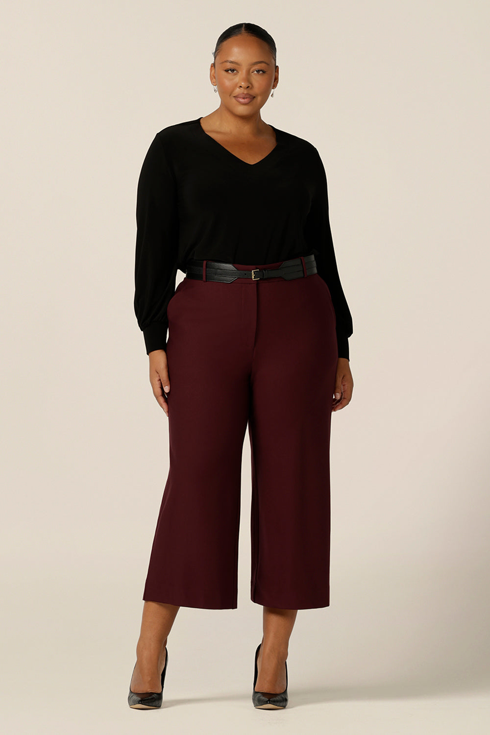 A size 18, curvy woman wears wide leg, cropped length, tailored pants in Mulberry ponte jersey with a long sleeve, V neck top in black jersey. Made in Australia by Australian and New Zealand women's clothing label, L&F, these easy care pants work for corporate wear and weekend wear.