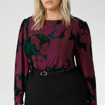 The Fuchsia Maya print is on a soft touch jersey fabric with print details in deep fuchsia, green, terracotta and black. The fabric has soft stretch. Plus size model wears her long sleeved top tucked into black workwear skirt. Available in sizes 8-24.