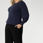 Feminine cut knit top features a boat neckline and full-length bellow sleeves with soft gathers at the shoulders and tailored darts at the wrists, adding gentle volume without the bulk. Subtle shaping through the body and bust darts create a flattering, close-to-body fit that moves easily from work to weekend. Available in sizes 8-24.