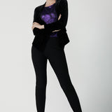 A size 10 woman wears the Zara top in purple metallic fabric. With balloon sleeves and a boat neckline. Styled back with black brooklyn ponte pants. The perfect cocktail suit set made in Australia for women size 8-24