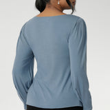 The boat neckline frames the collarbone with subtle sophistication, while tailored bust darts and a close-to-body shape enhance the fit without feeling restrictive. Crafted with attention to detail, the full-length sleeves feature gentle gathers at the shoulder and a wrist dart, adding soft volume and movement—ideal for styling under outerwear without bulk.
