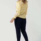 Back view of a size 10 woman wears a Zara Top in Yellow Swirl silk. A long sleeve blouse with fashion sleeve and made in 100% silk. Made in Australia for women size 8-24. Styled back with the Indi Tall Pant in Navy.