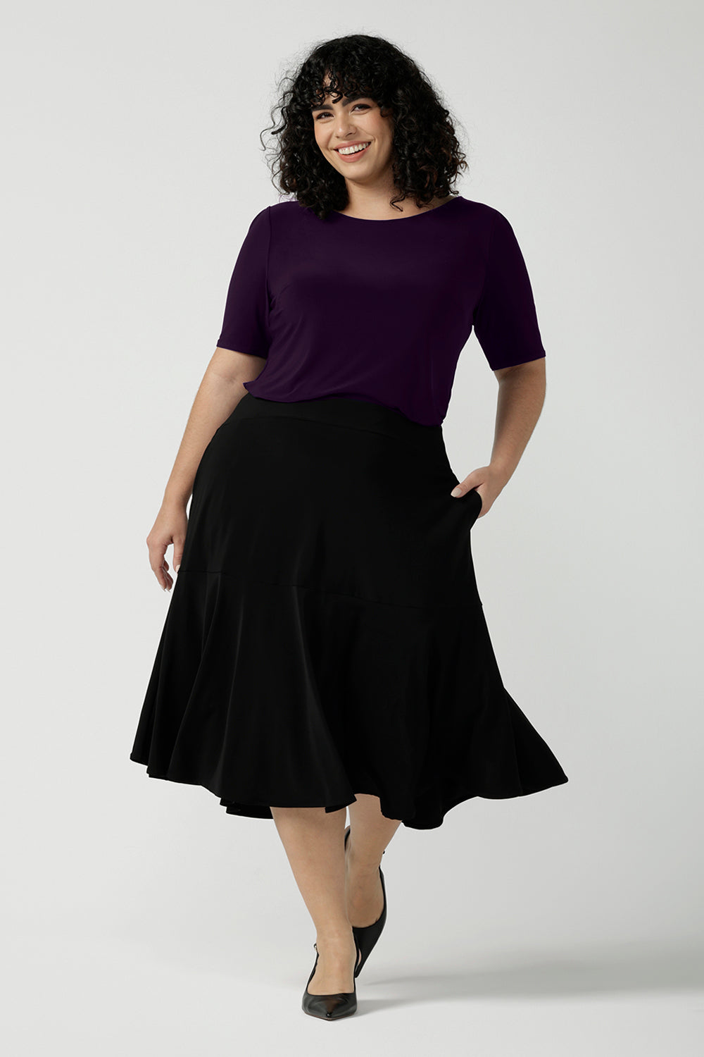 Size 18 woman wears the Ziggy top in Amethyst. Round neckline top with elbow length sleeves, sleeve head tuck. Soft comfortable jersey for stylish workwear. Made in Australia size 8 to 24.