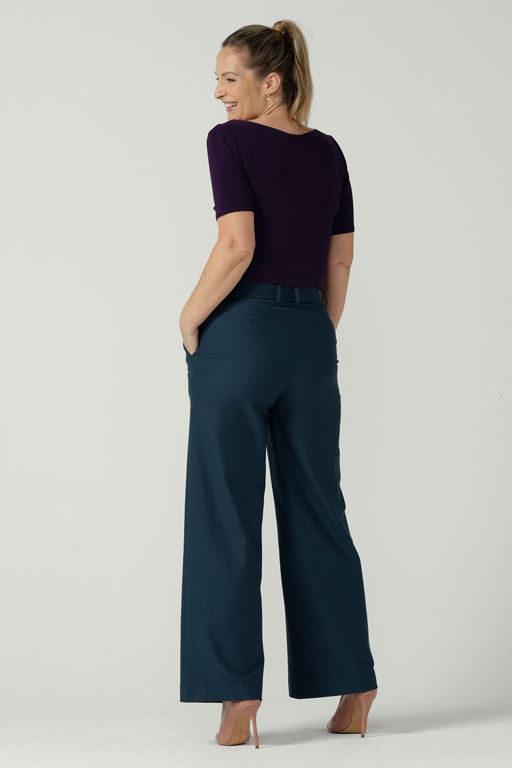 Back view of a Size 10 woman wears the Ziggy top in Amethyst, a boat neckline style with a pleat tuck on the sleeve head and slight curve hem. Made in Australia for women size 8 - 24.