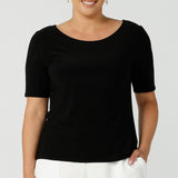 A curvy size 12 woman wears a jersey Ziggy top with a round neckline and elbow-length sleeve and curved hemline. The perfect work top for comfortable corporate wear. Made in Australia for Australian fashion label Leina & Fleur sizes 8 -24.
