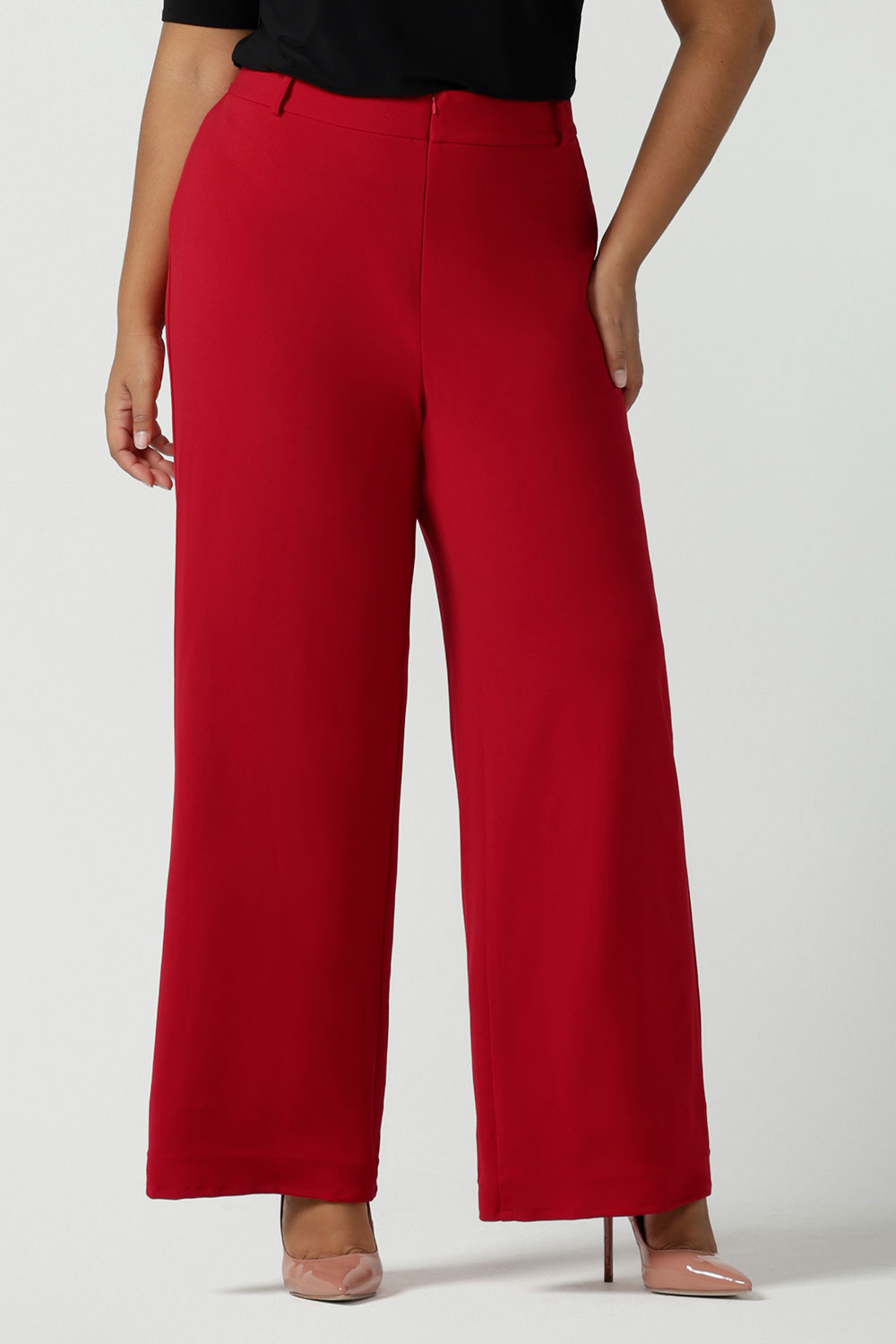 Close up of a size 16 woman wears the Drew pant in red, high waist and invisible fly front. Tailored belt loops and wide leg. Made in Australia for women. Stylish corporate wear for women. Made in Australia size 8 - 24.