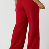 Back view of a size 16 woman wears the Drew pant in red, high waist and invisible fly front. Tailored belt loops and wide leg. Made in Australia for women. Stylish corporate wear for women. Made in Australia size 8 - 24.