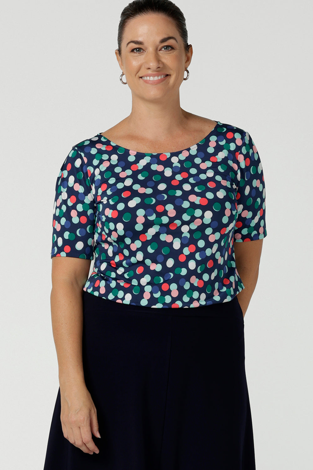 Size 12 woman wears Ziggy Top in Blue Bubbles. A boat neckline style made in soft jersey with a above elbow sleeve and double turned neckline. Style back with Navy Berit skirt. Made in Australia for women size 8 - 24. 