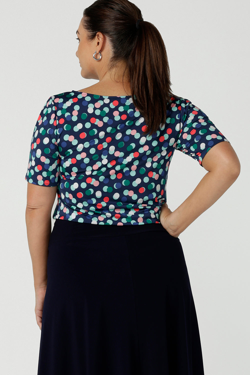 Back view of a size 12 woman wears Ziggy Top in Blue Bubbles. A boat neckline style made in soft jersey with a above elbow sleeve and double turned neckline. Style back with Navy Berit skirt. Made in Australia for women size 8 - 24.