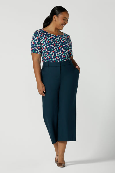 Size 16 curvy woman wears Ziggy Top in Blue Bubbles. A boat neckline style made in soft jersey with a above elbow sleeve and double turned neckline. Styled back with Petrol Yael tailored pants. Made in Australia for women size 8 - 24.