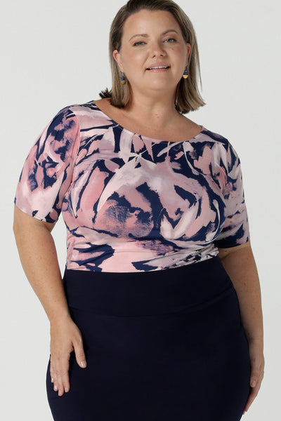 Curvy woman wears the Ziggy top in a size 18 with a boat neckline, elbow length sleeves and an abstract print on a Navy base. With painterly brush strokes. Styled back with the Andi tube skirt in Navy. Size 8 - 24.