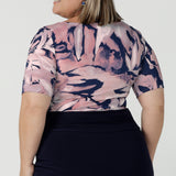 Back view of a curvy woman wears the Ziggy top in a size 18 with a boat neckline, elbow length sleeves and an abstract print on a Navy base. With painterly brush strokes. Styled back with the Andi tube skirt in Navy. Size 8 - 24