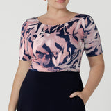 A curvy woman wears the Ziggy top in a size 18 with a boat neckline, elbow length sleeves and an abstract print on a Navy base. With painterly brush strokes. Styled back with the Andi tube skirt in Navy. Inclusive sizing for women Size 8 - 24