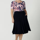 A size 12 woman wears the Ziggy top with a boat neckline, elbow length sleeves and an abstract print on a Navy base. With painterly brush strokes. Styled back with the Andi tube skirt in Navy. Inclusive sizing for women Size 8 - 24