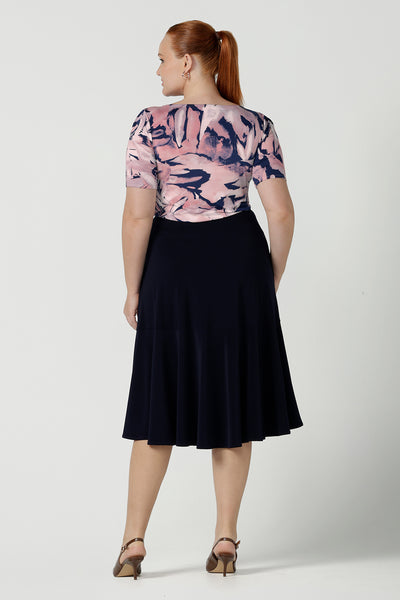 Back view of a size 12 woman wears the Ziggy top with a boat neckline, elbow length sleeves and an abstract print on a Navy base. With painterly brush strokes. Styled back with the Andi tube skirt in Navy. Inclusive sizing for women Size 8 - 24