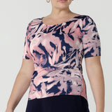 A curvy woman wears the Ziggy top in a size 18 with a boat neckline, elbow length sleeves and an abstract print on a Navy base. With painterly brush strokes. Styled back with the Andi tube skirt in Navy. Inclusive sizing for women Size 8 - 24