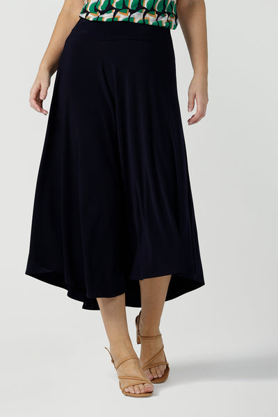 Close up of a size 10, 40 plus woman wears an asymmetric skirt in navy jersey. Worn with a geometric print, boat neck top with short sleeves, this comfortable jersey skirt works for work wear and eveningwear. Made in Australia by women's clothing brand, Leina & Fleur in petite, mid size and plus sizes.