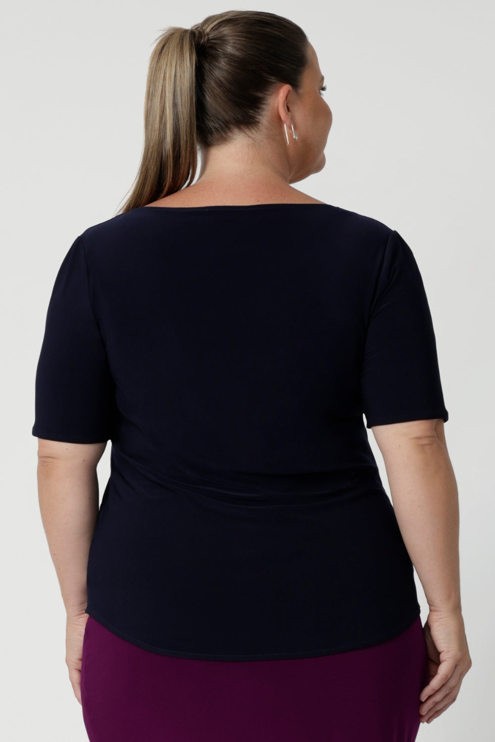 Back view of size 18 woman wears navy top with elbow length sleeves paired with magenta skirt and heels for an elevated look for work. Available in size 8-24 from woman's clothing brand Leina & Fleur.