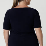 Back view of size 18 woman wears navy top with elbow length sleeves paired with magenta skirt and heels for an elevated look for work. Available in size 8-24 from woman's clothing brand Leina & Fleur.