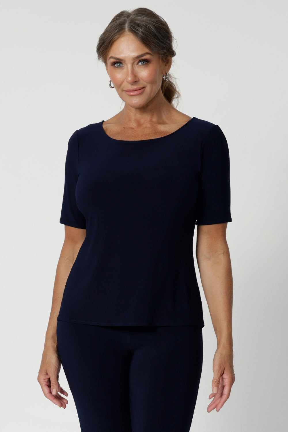 Over 40's woman wears navy top featuring elbow sleeves, straight hem & coop neck. Can be styled with with printed pants and heels for an elevated look or with sneakers for a casual look. Available in sizes 8-24.