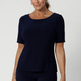 Over 40's woman wears navy top featuring elbow sleeves, straight hem & coop neck. Can be styled with with printed pants and heels for an elevated look or with sneakers for a casual look. Available in sizes 8-24.