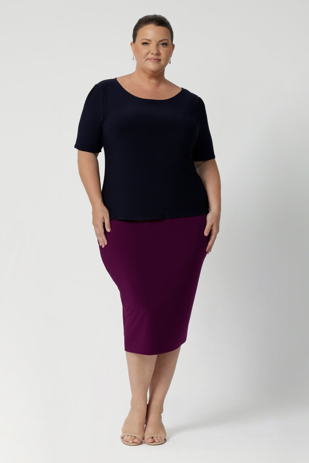 Plus size woman wears navy workwear top featuring elbow sleeves, straight neckline and straight hem. Australia made from easy care dry touch jersey fabric, in sizes 8-24.