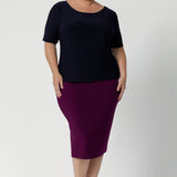 Plus size woman wears navy workwear top featuring elbow sleeves, straight neckline and straight hem. Australia made from easy care dry touch jersey fabric, in sizes 8-24.