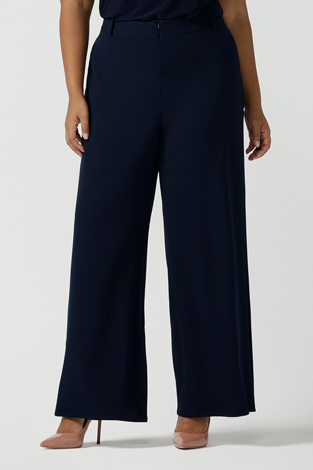 Close up of a size 10 model wears the Navy wide leg pant with navy scuba crepe. High waisted and tailored with belt loops. Stylish and corporate workwear for women size 8 - 24.. Made in Australia.