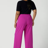 Back view of a size 16 Woman wears the Drew Pant in Fuchsia. A high waist tailored pant with matching suit blazer. Made in Australia for women size 8 - 24.Styled back with a black Ziggy top. 