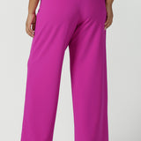 Back view of a size 16 Woman wears the Drew Pant in Fuchsia. A high waist tailored pant with matching suit blazer. Made in Australia for women size 8 - 24.