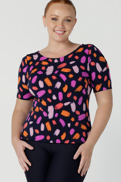 Size 12 happy woman wears the Ziggy top in Palette. A boat neckline style with short sleeves and shoulder tucks. A great work to weekend top for women. Palette print features a brush stroke print of fuchsia, lilac, red and orange . Made in Australia for women size 8 to 24.